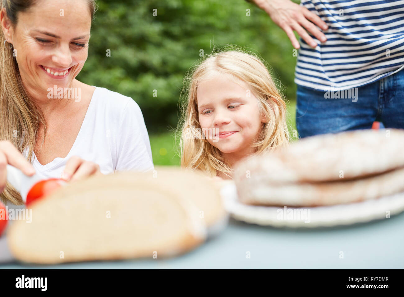 Mother and daughter prepare snack or breakfast at the campsite Stock Photo