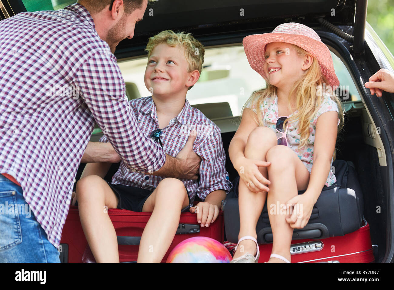 Children and father with luggage in the car together while preparing the trip Stock Photo