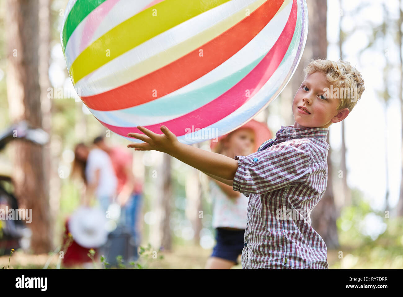 Boy is playing with a big colorful ball in the garden or park in the summer holidays Stock Photo