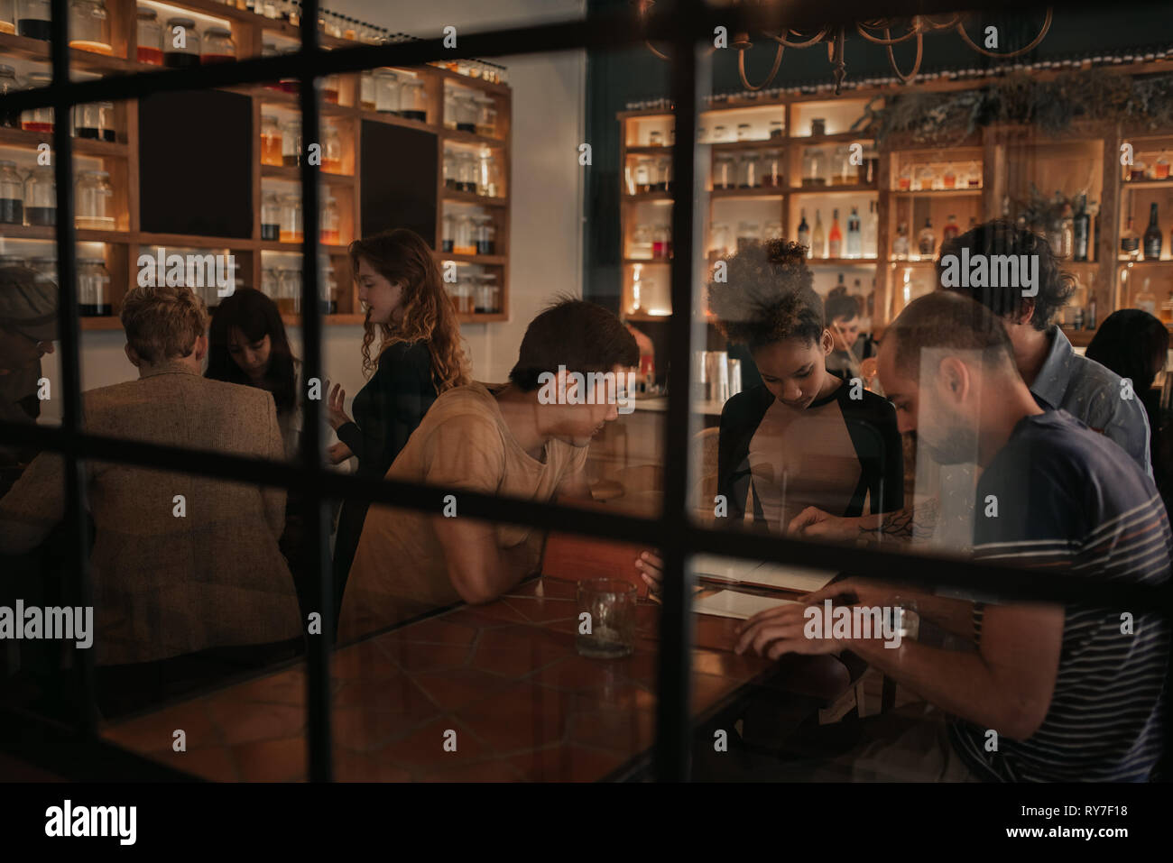 Diverse young friends ordering drinks in a bar at night Stock Photo