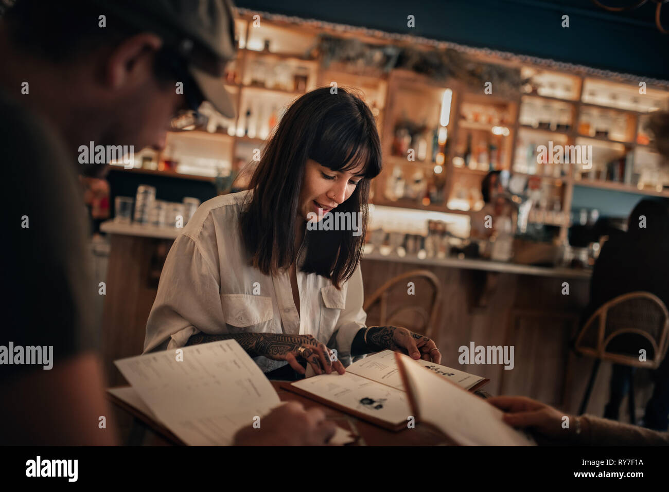 Friends reading drinks menus in a bar at night Stock Photo