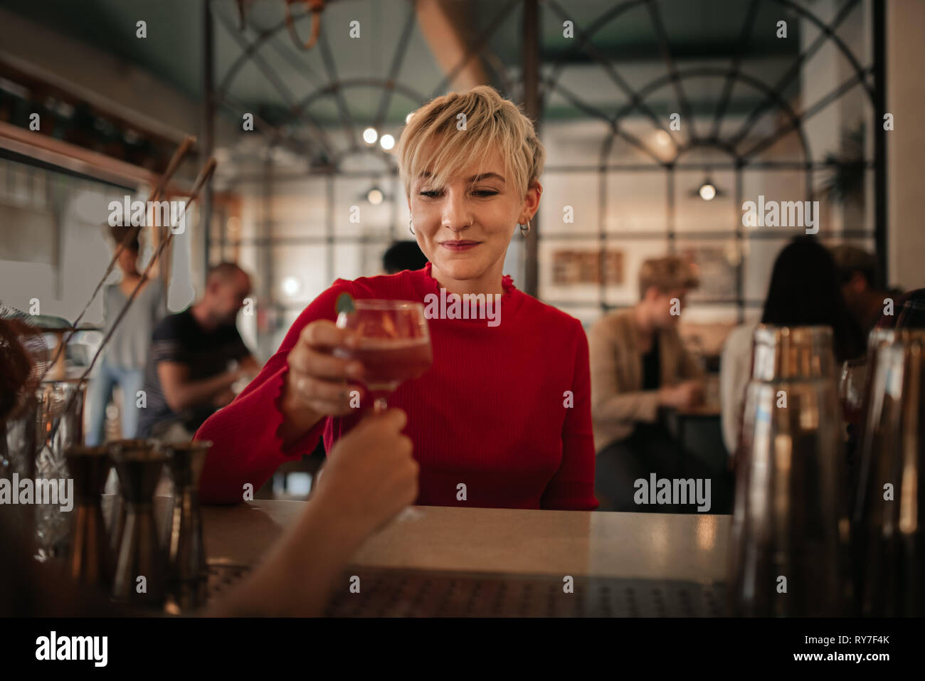 Smiling young woman getting drinks in a bar at night Stock Photo