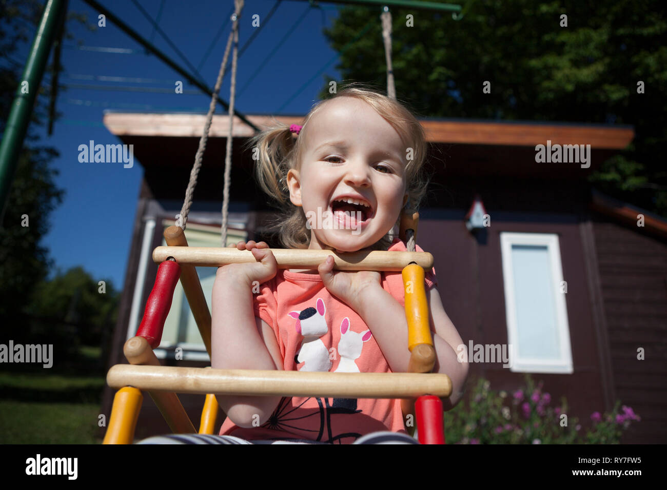 Happy child on a wooden swing in a back yard Stock Photo