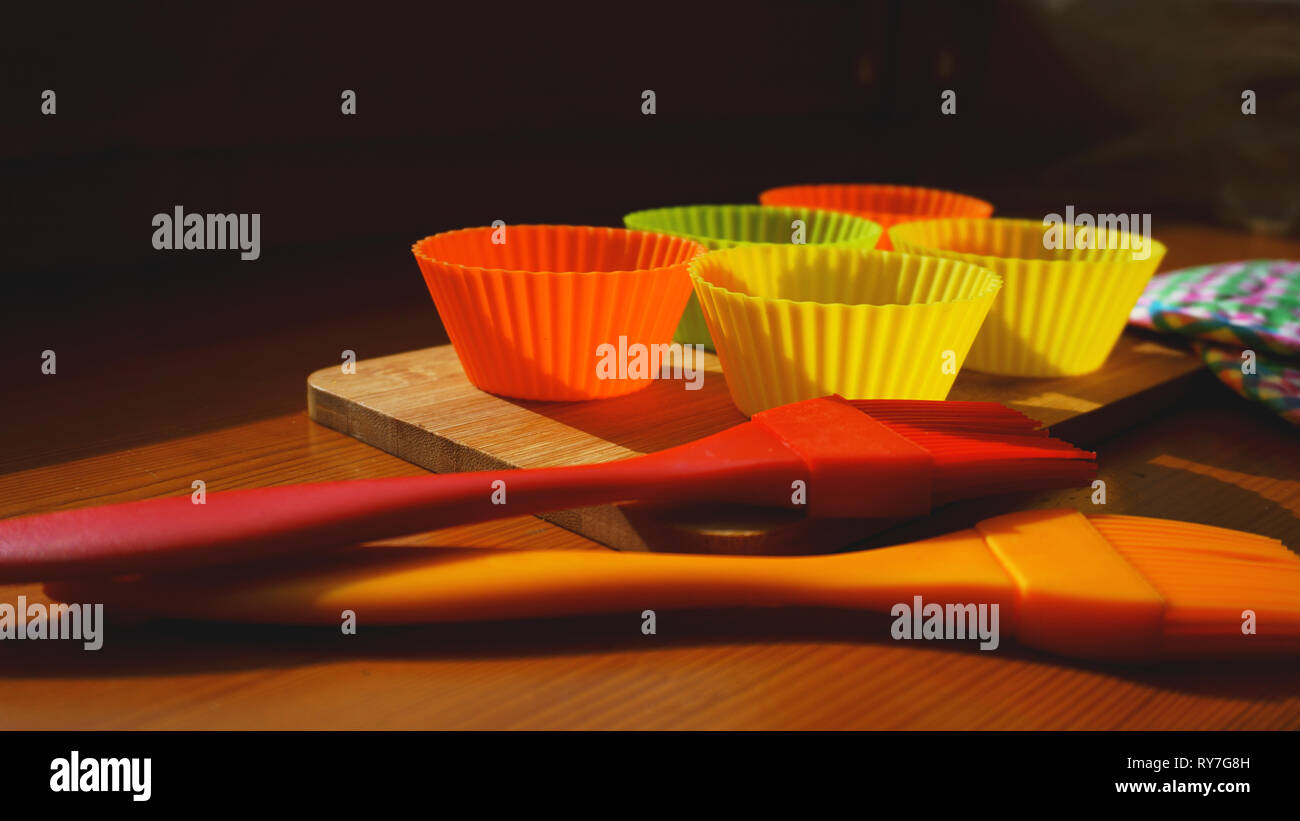 Silicone brush and cupcake liners on wooden table. Kitchen and cooking concept on wooden background Stock Photo