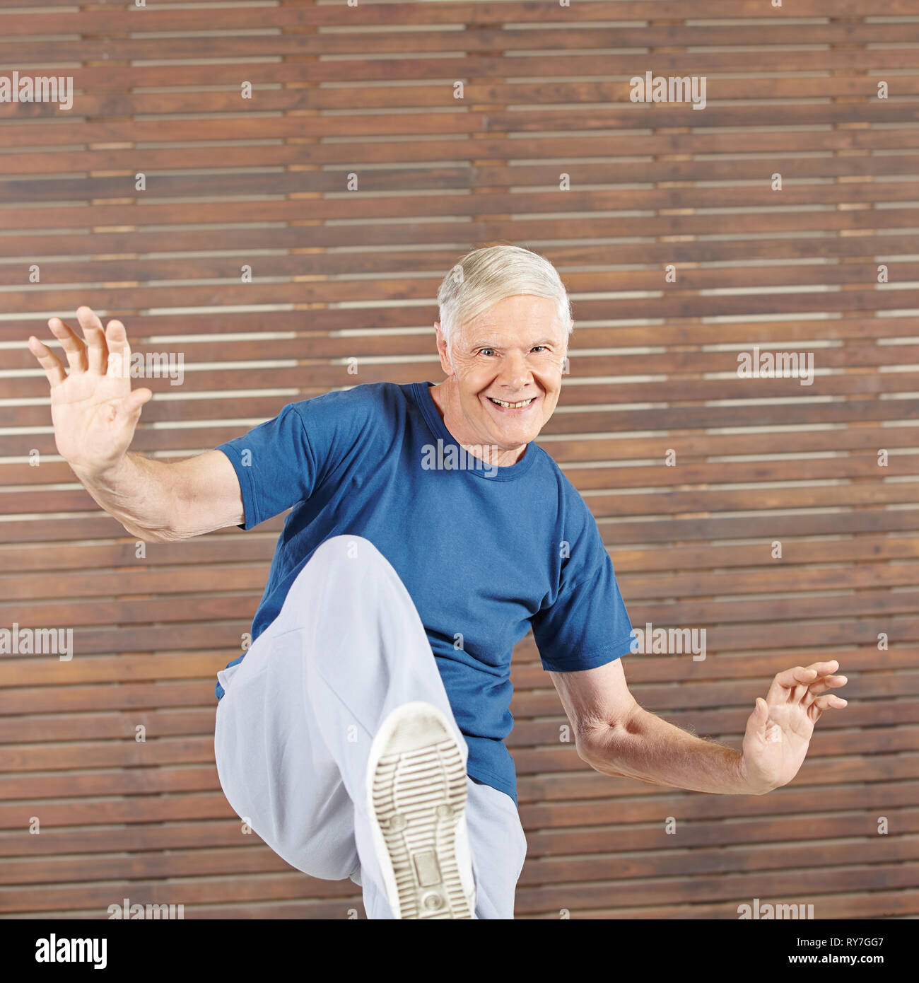 Old smiling man stays active in the gym by exercise Stock Photo