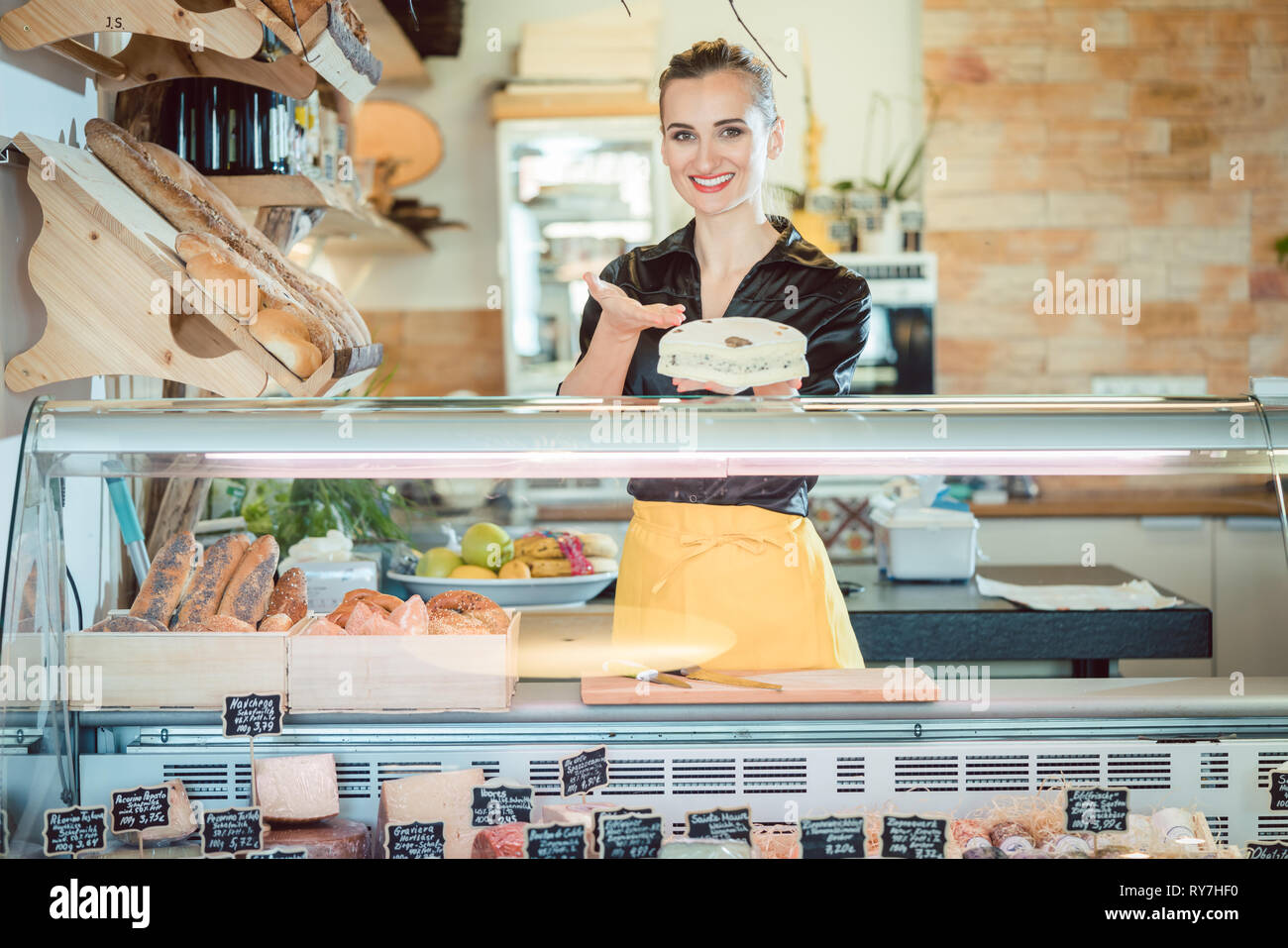 Salesgirl selling cheese in deli or supermarket Stock Photo