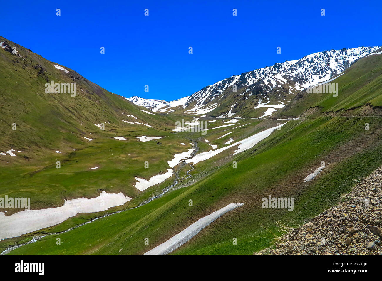 Car Road Toward Song Kul Lake with Snow Capped Mountains Landscape Stock Photo