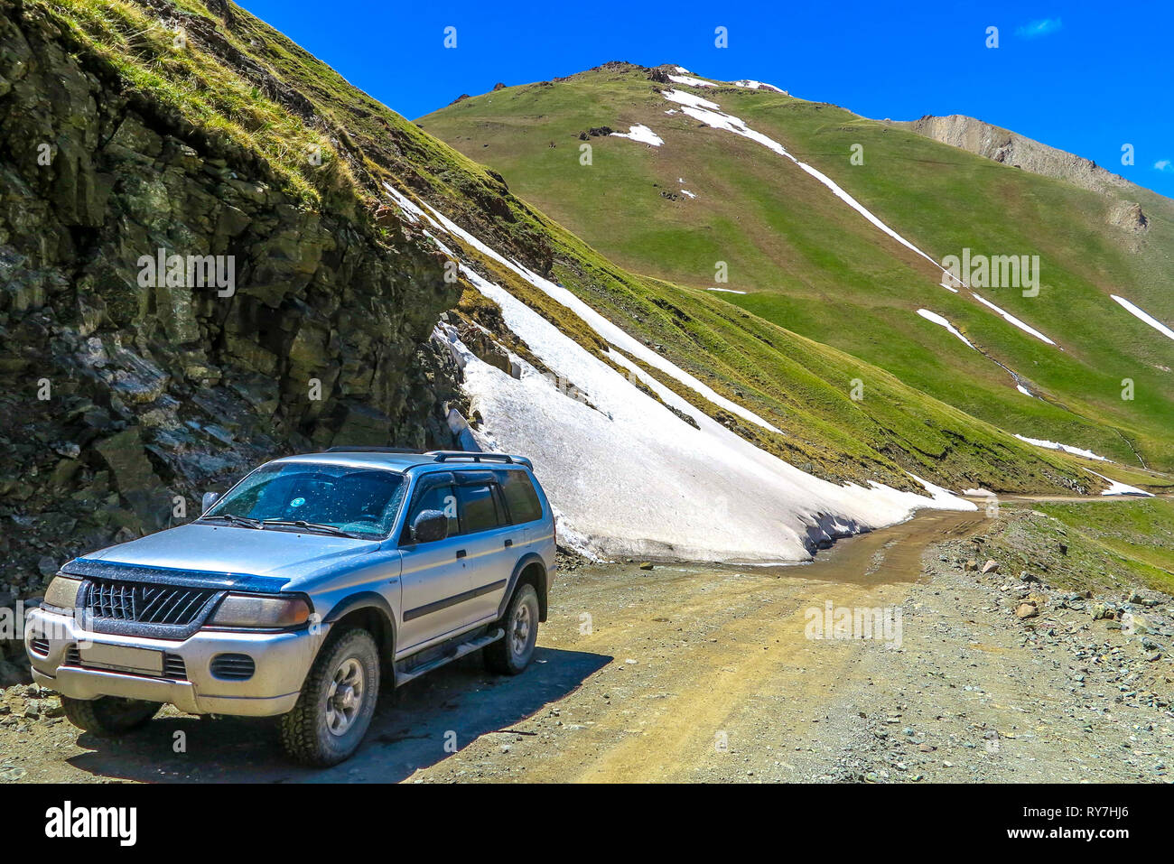 Jeep Car Road Toward Song Kul Lake with Snow Capped Mountains Landscape Stock Photo