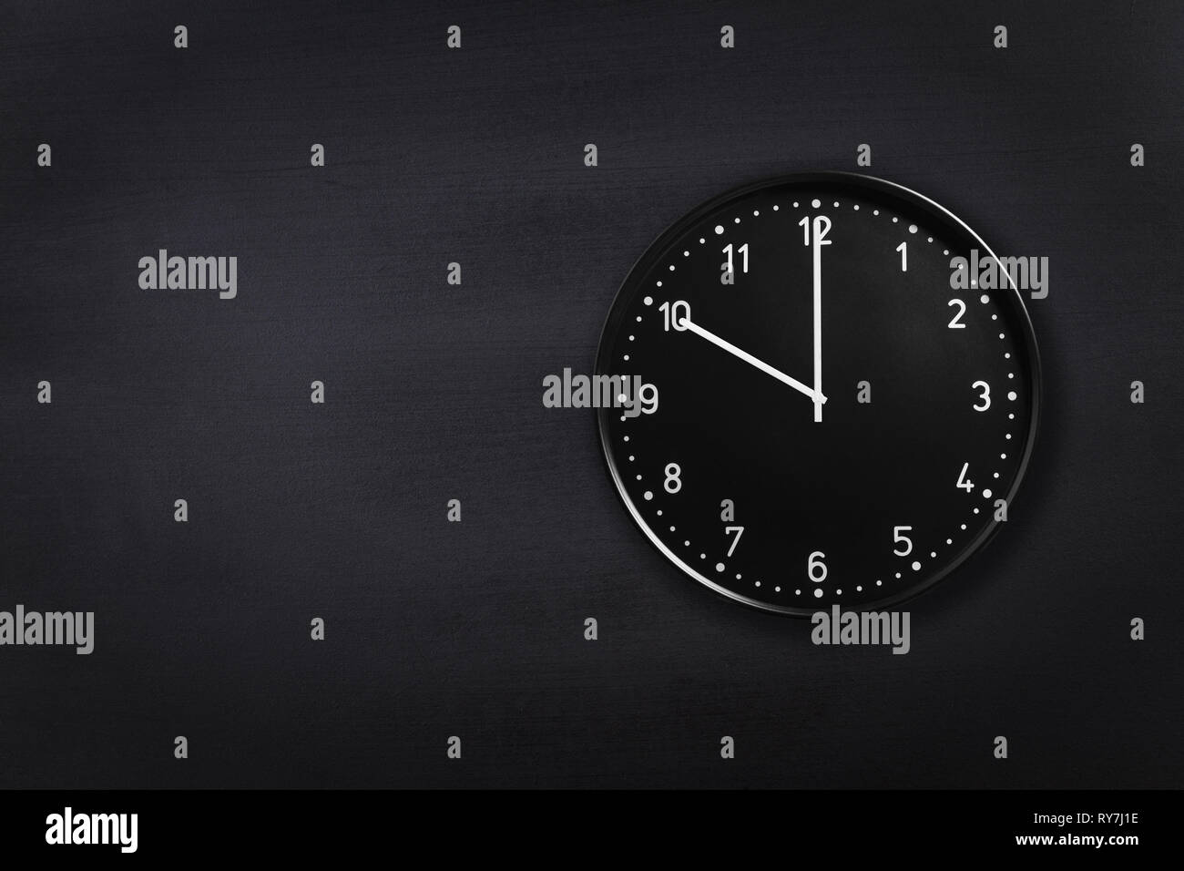 Black clock showing ten o'clock on black chalkboard background. Office