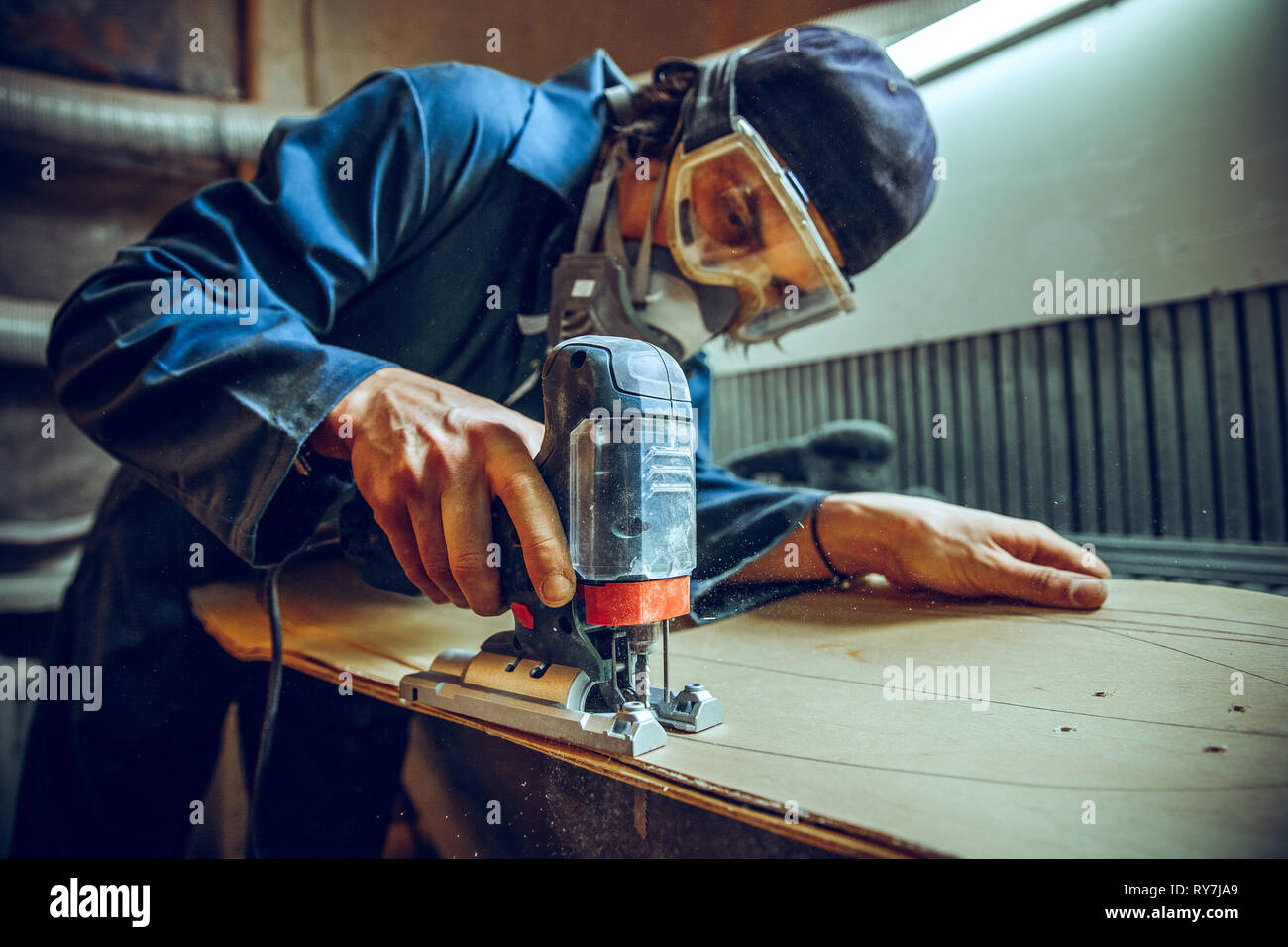 Carpenter using circular saw for cutting wooden boards. Construction details of male worker or handy man with power tools Stock Photo