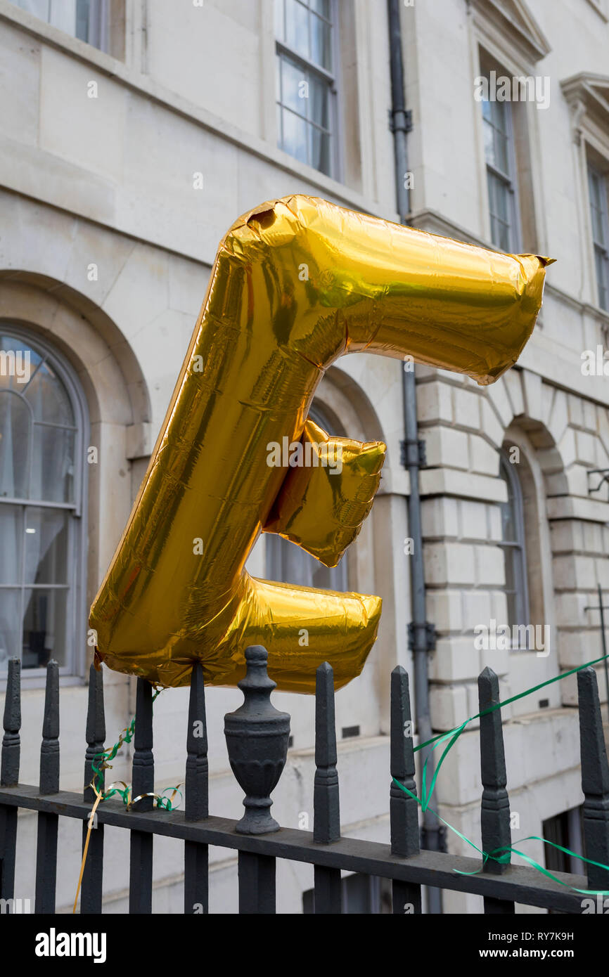 An E balloon (representing the concept of remaining in Europe) blows in the wind on railings during a pro-EU brexit protest opposite Parliament, on 11th March 2019, in Westminster, London, England. Stock Photo