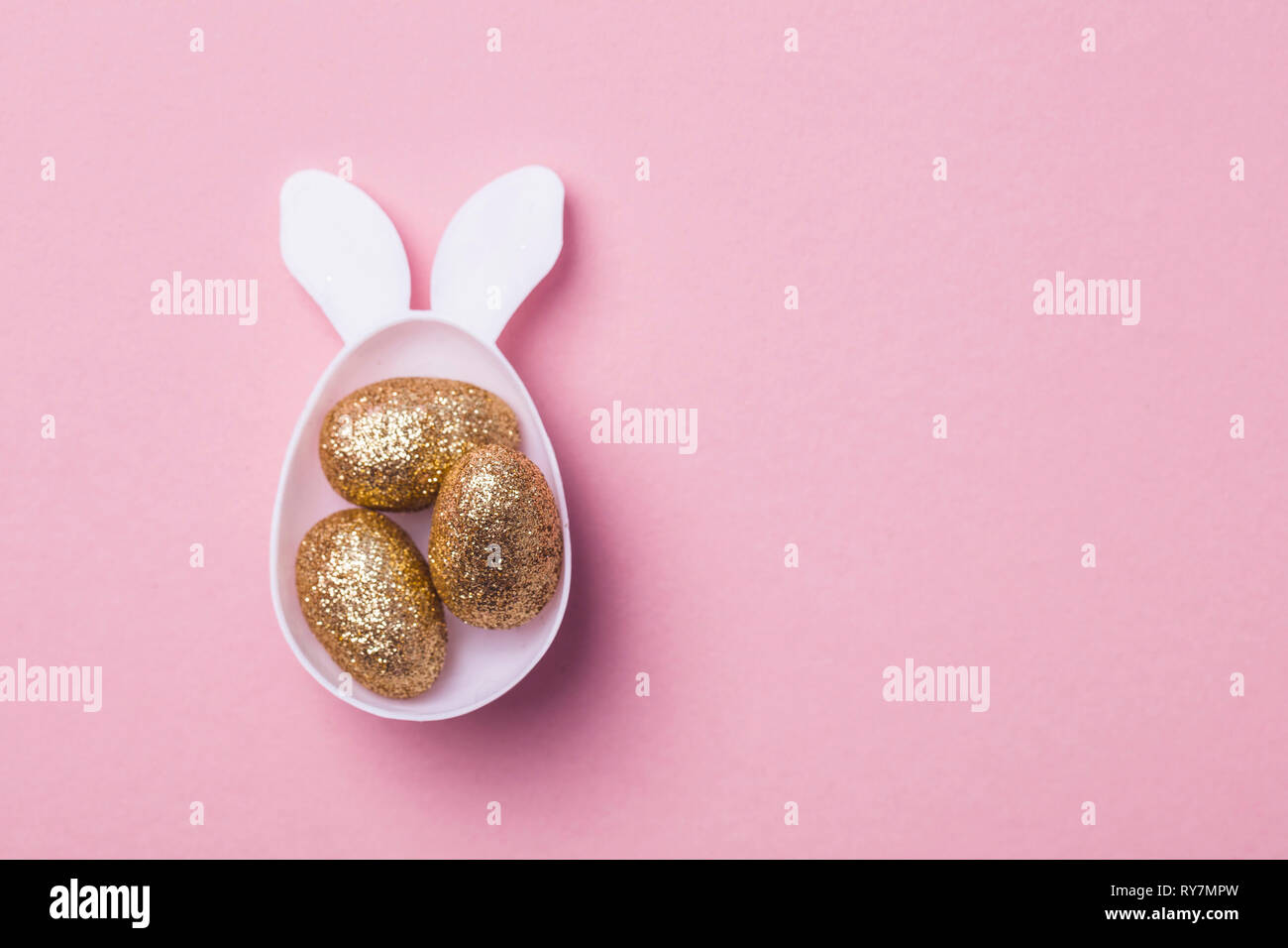 Gold glitter eggs in a white easter bunny egg shape with ears Stock