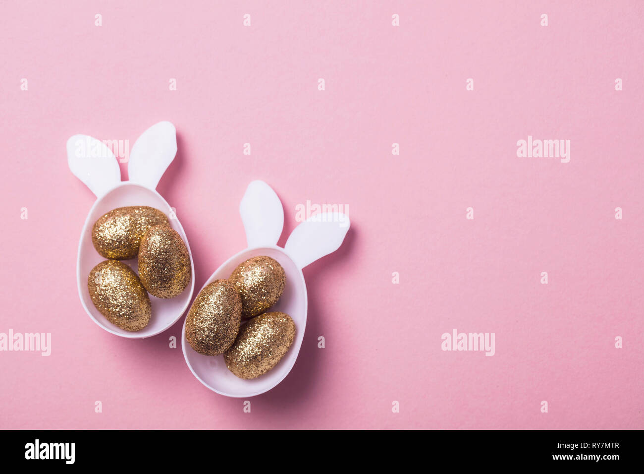 Gold glitter eggs in a white easter bunny egg shape with ears Stock
