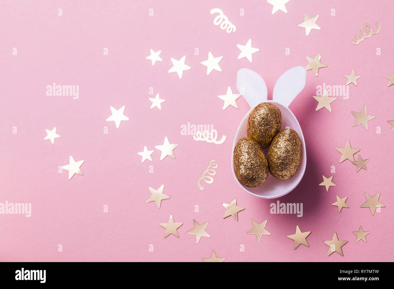 Gold glitter eggs in a white easter bunny egg shape with ears Stock