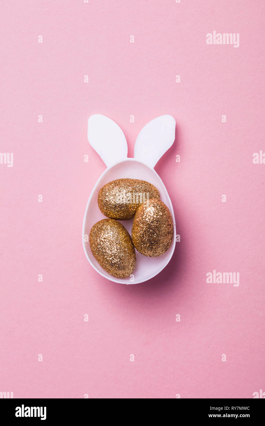 Gold glitter eggs in a white easter bunny egg shape with ears Stock