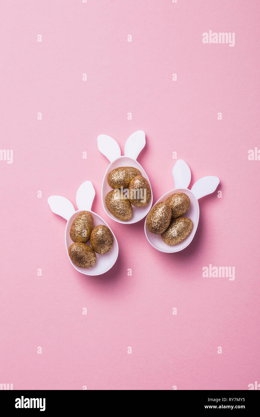 Gold glitter eggs in a white easter bunny egg shape with ears Stock