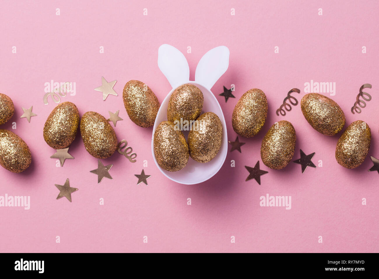 Gold glitter eggs in a white easter bunny egg shape with ears Stock