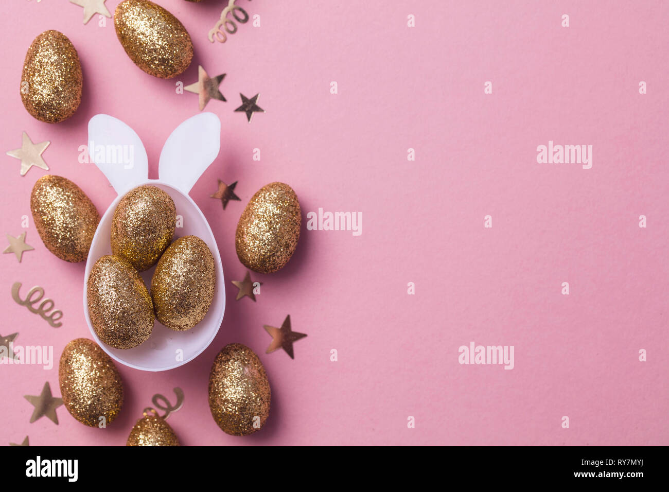 Gold glitter eggs in a white easter bunny egg shape with ears Stock