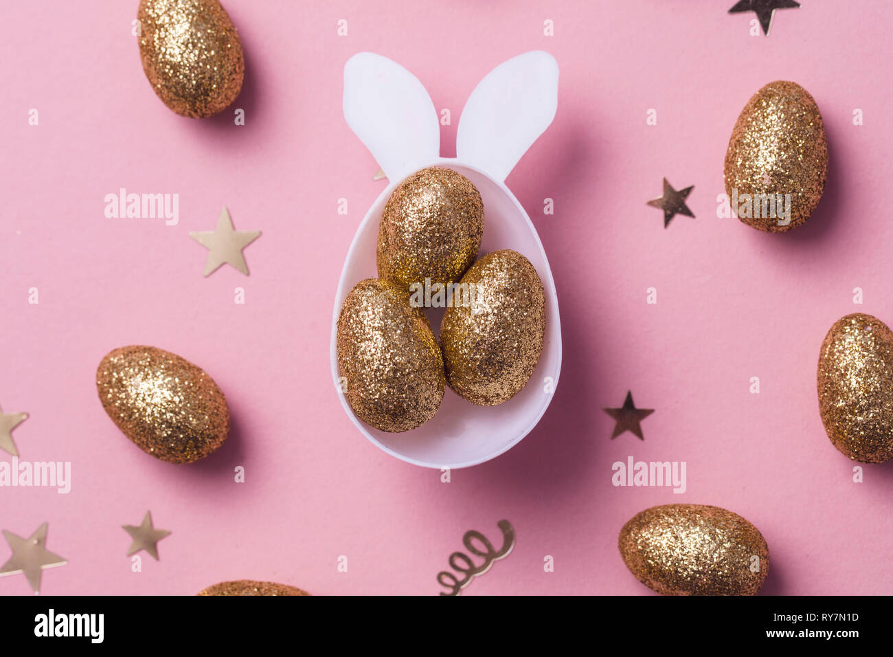 Gold glitter eggs in a white easter bunny egg shape with ears Stock