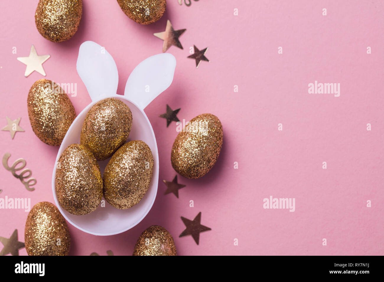Gold glitter eggs in a white easter bunny egg shape with ears Stock Photo