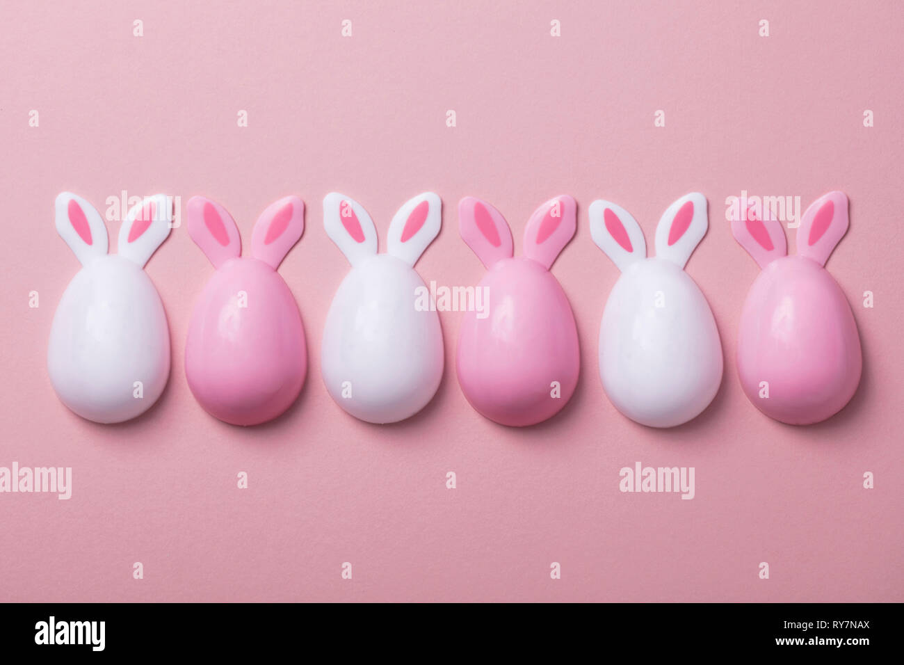 Easter eggs with bunny ears on a pastel pink background Stock Photo - Alamy