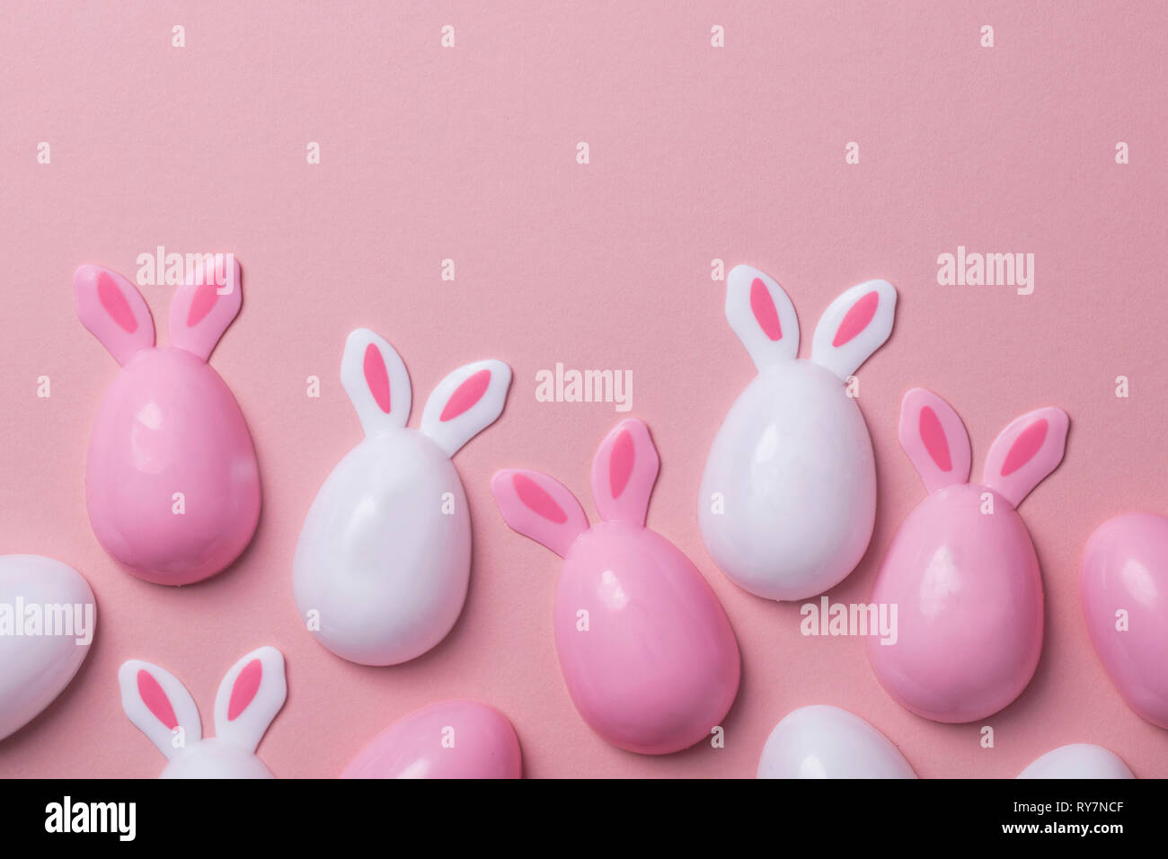 Easter eggs with bunny ears on a pastel pink background Stock Photo - Alamy