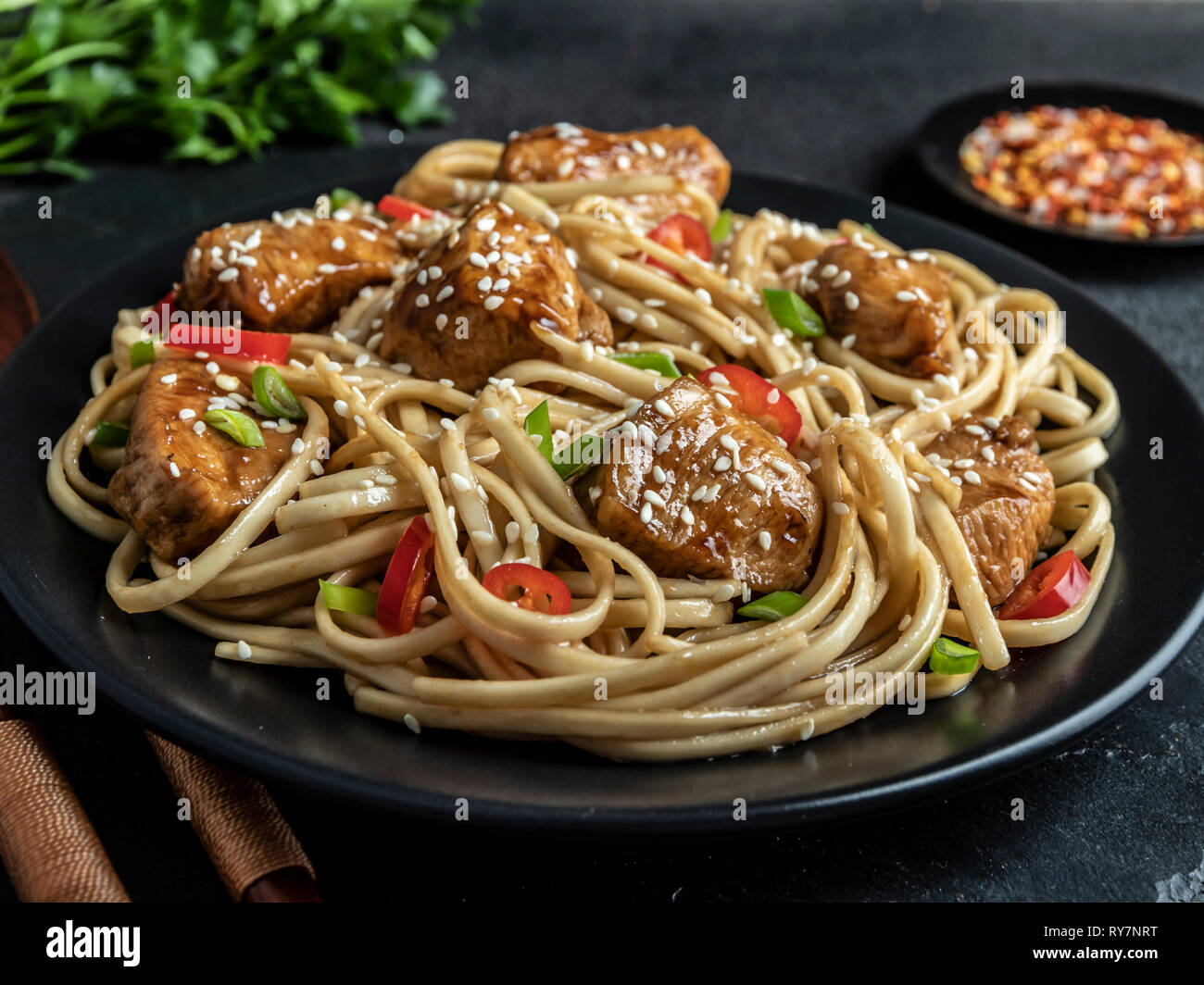 Asian noodles with chicken teriyaki , sesame, rustic stone background. Closeup. Chinese/Japanese