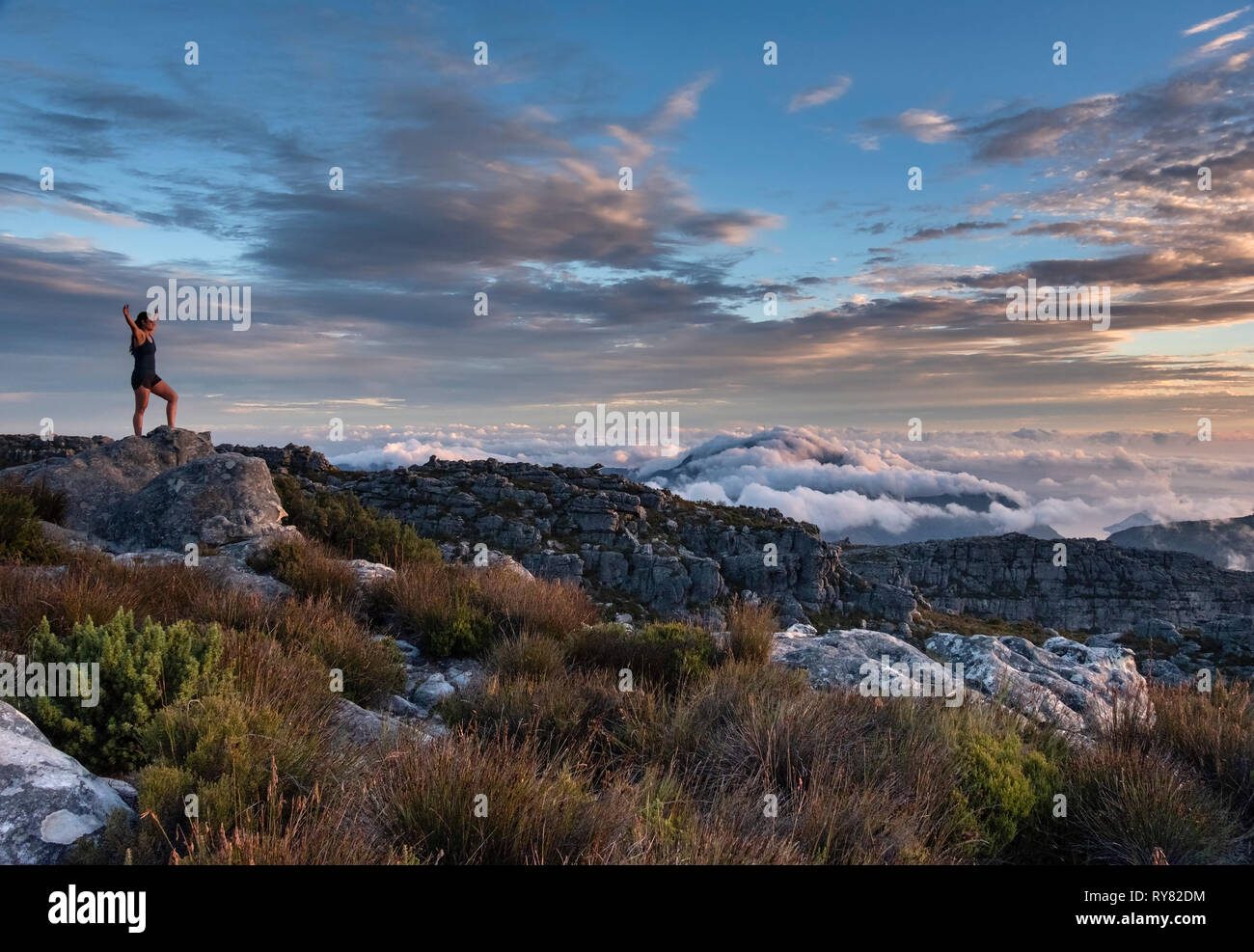 A young woman practices yoga on Table Mountain at sunset, Cape Town, Western Cape, South Africa Stock Photo
