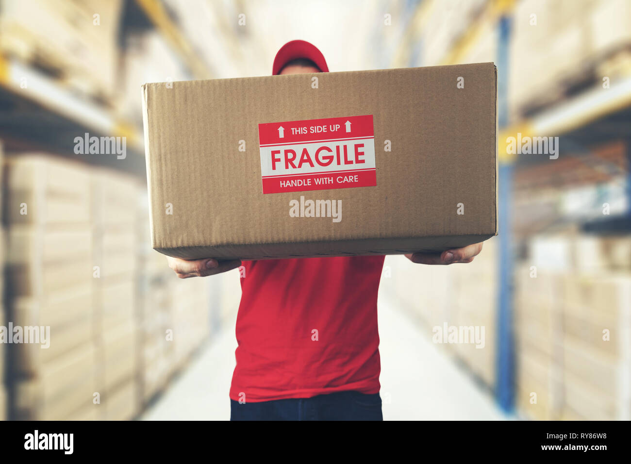 logistics warehouse worker holding package with fragile items Stock Photo