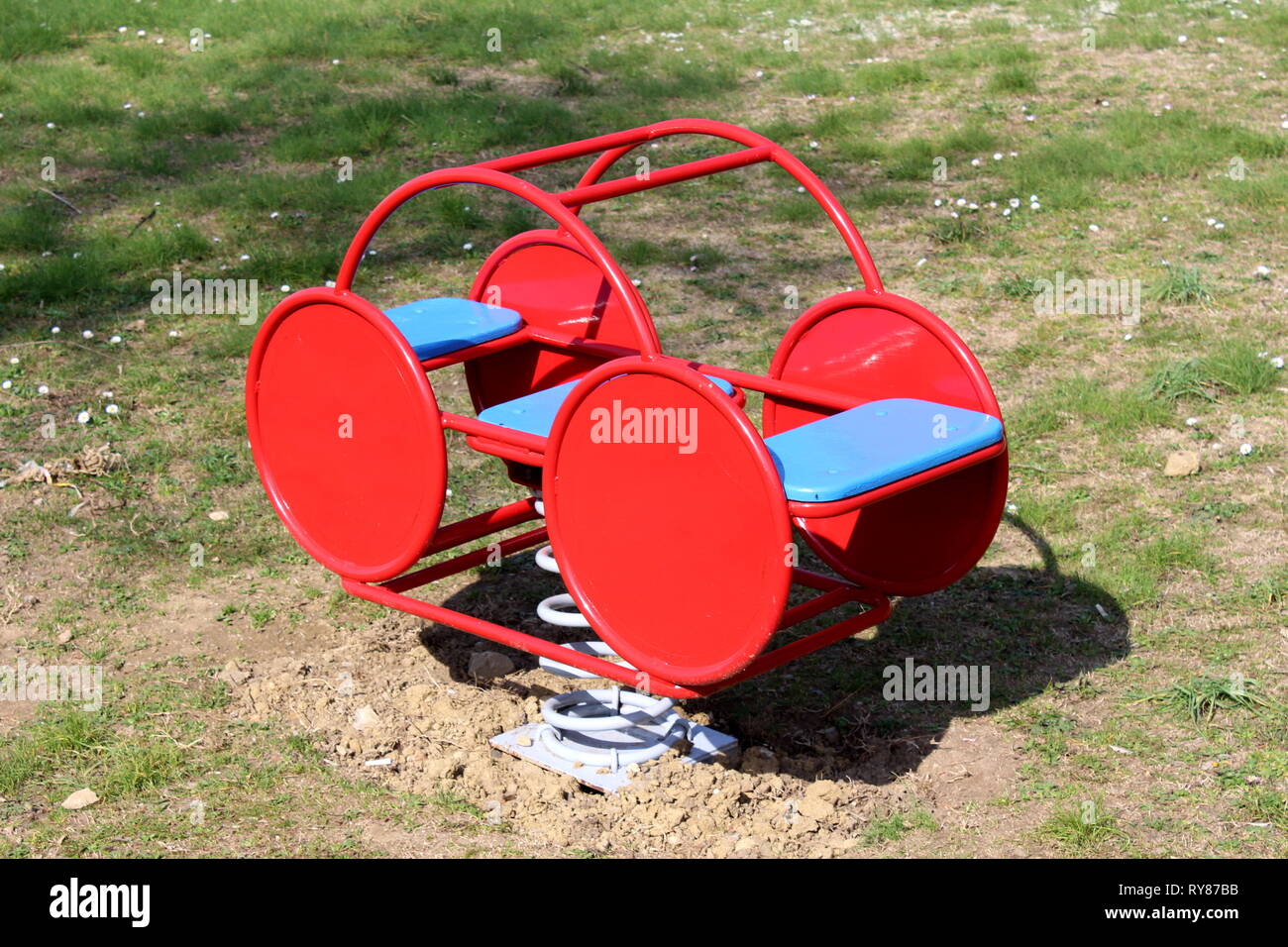 Red metal outdoor public playground equipment in shape of retro vintage