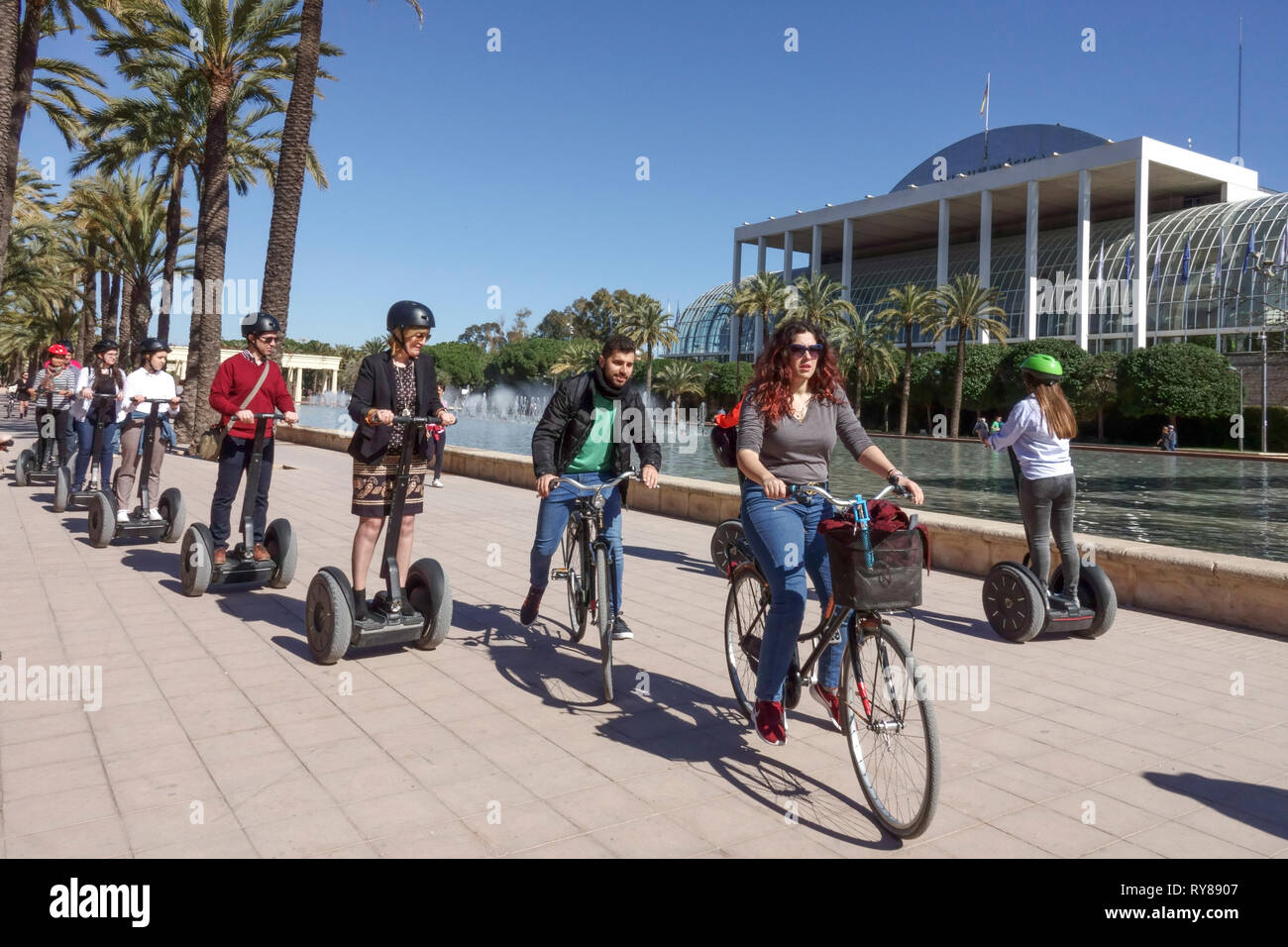 Spain Tourists Valencia Turia Park, People on bikes passing segways tour Place in front of Music Palace Valencia Spain bicycle city park people cycle Stock Photo