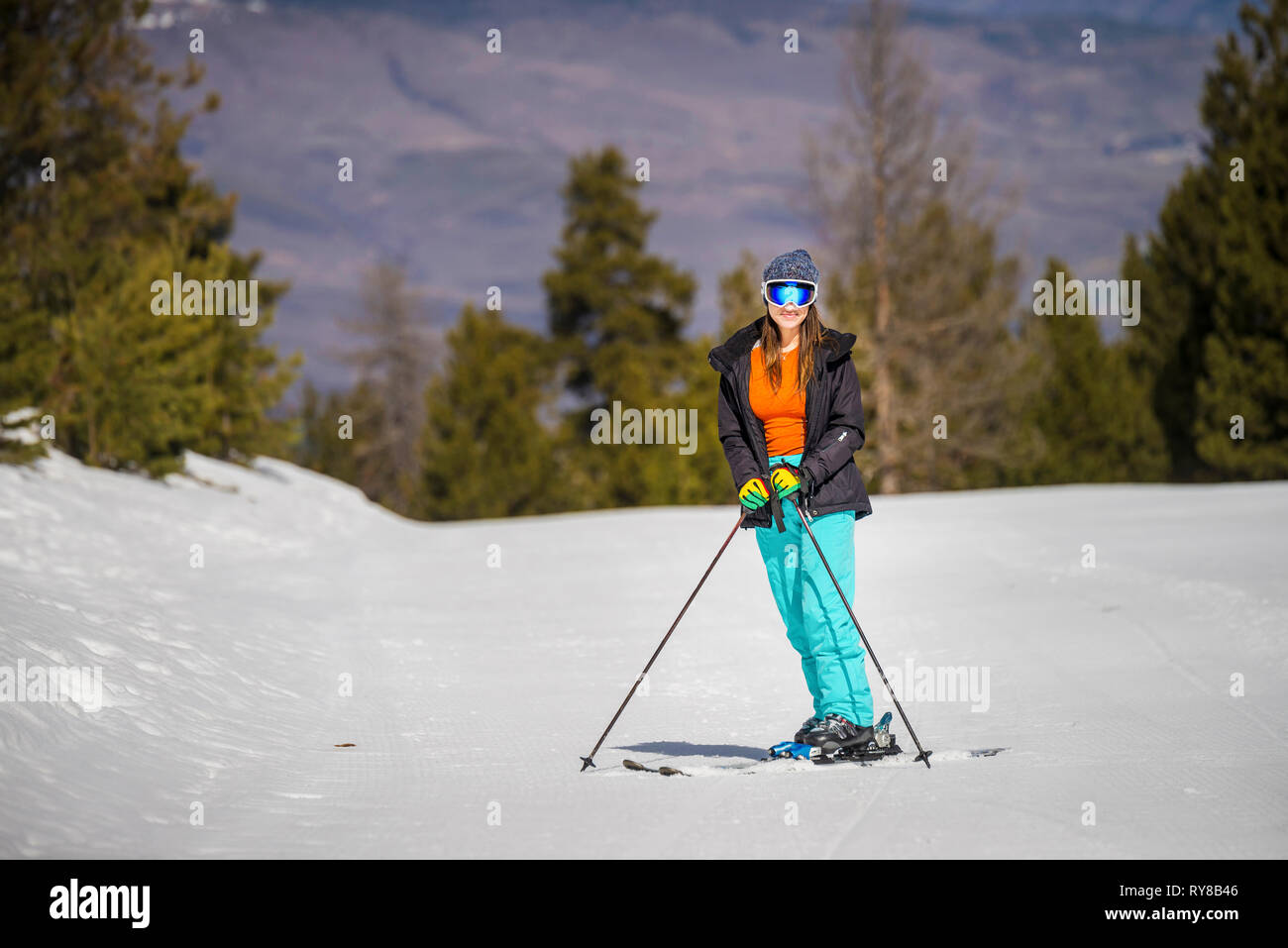 Woman skiing on snow covered field against mountain in forest Stock Photo