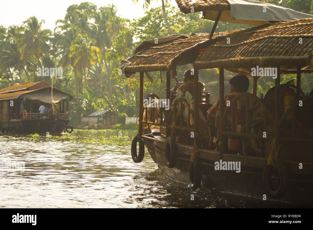 A tourboat operator falls in line and steers through the Kerala Backwaters, in south India. Stock Photo