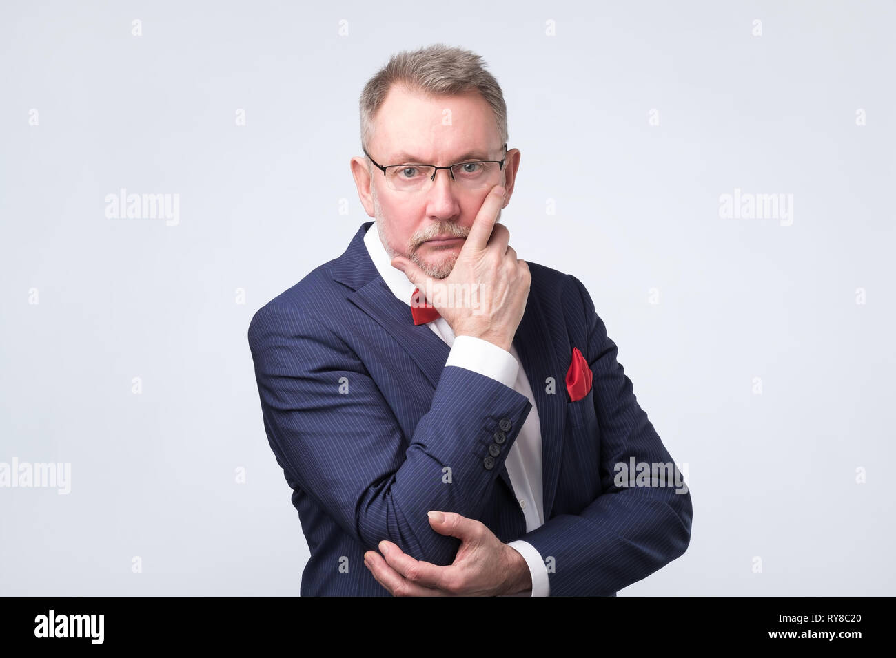 Senior european man in blue suit and glasses looking at camera Stock Photo