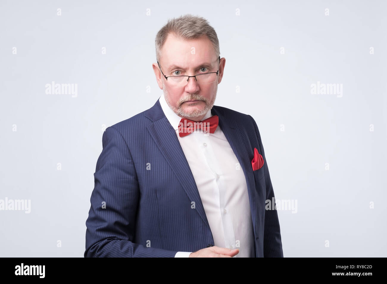 Senior european man in blue suit and glasses looking at camera Stock Photo