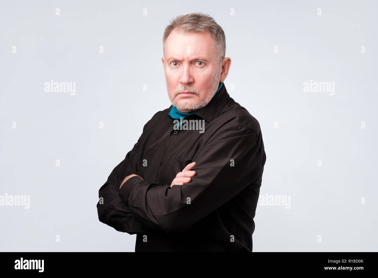 old man in black shirt with folded hands looking at camera with confidence Stock Photo