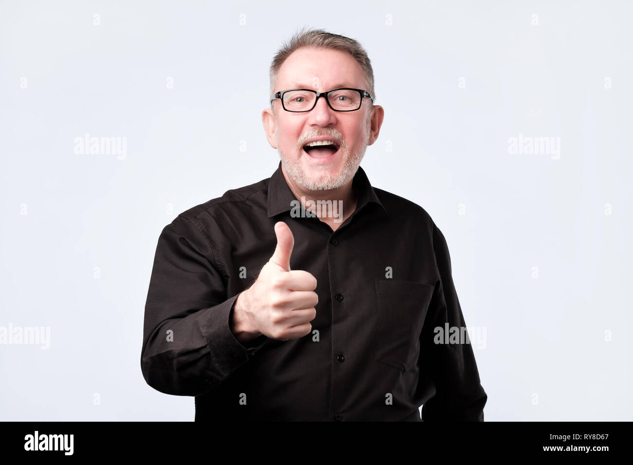senior handsome man in black shirt and glasses showing thumbs up gesture Stock Photo