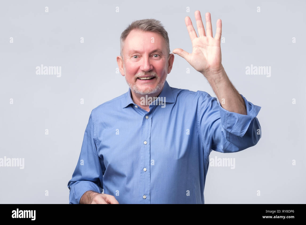 Portrait of a mature man in blue shirt wave hand welcome. Stock Photo