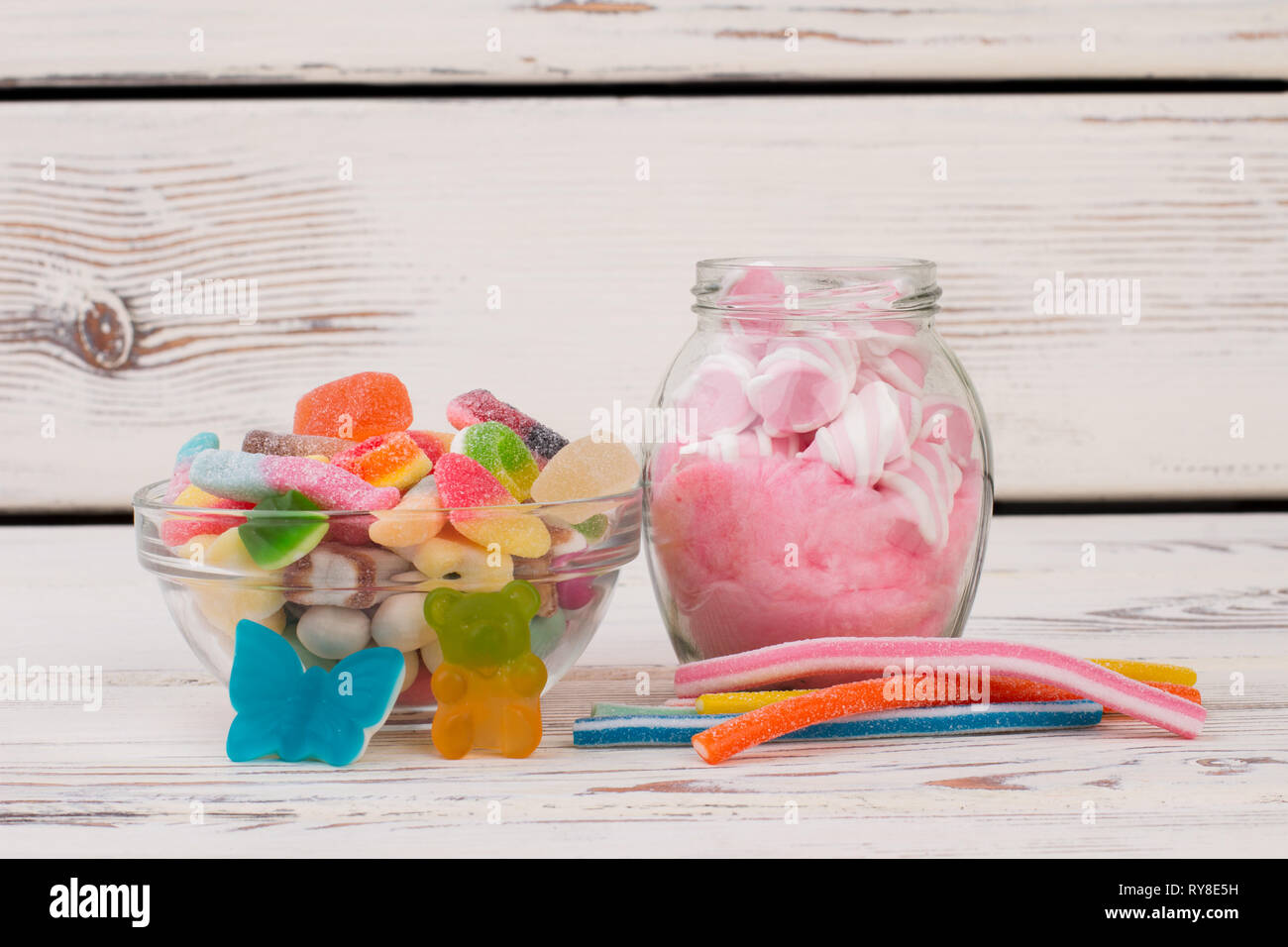 Multicolored candies and jellies on wooden background. Stock Photo