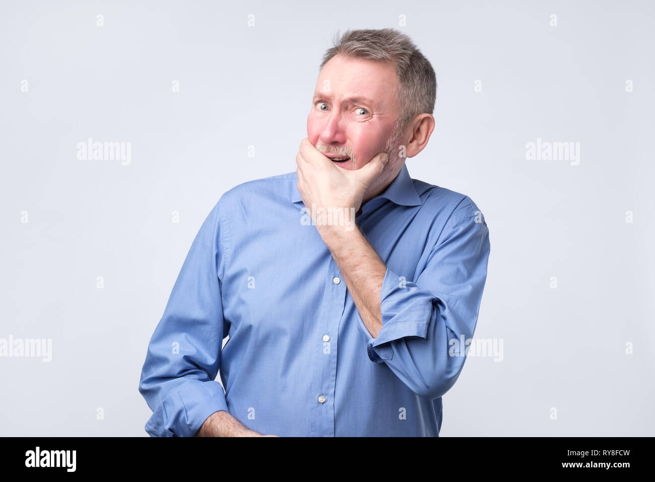 Caucasian senior grandfather curves lips, looks doubtfully, thinks what to do. Stock Photo