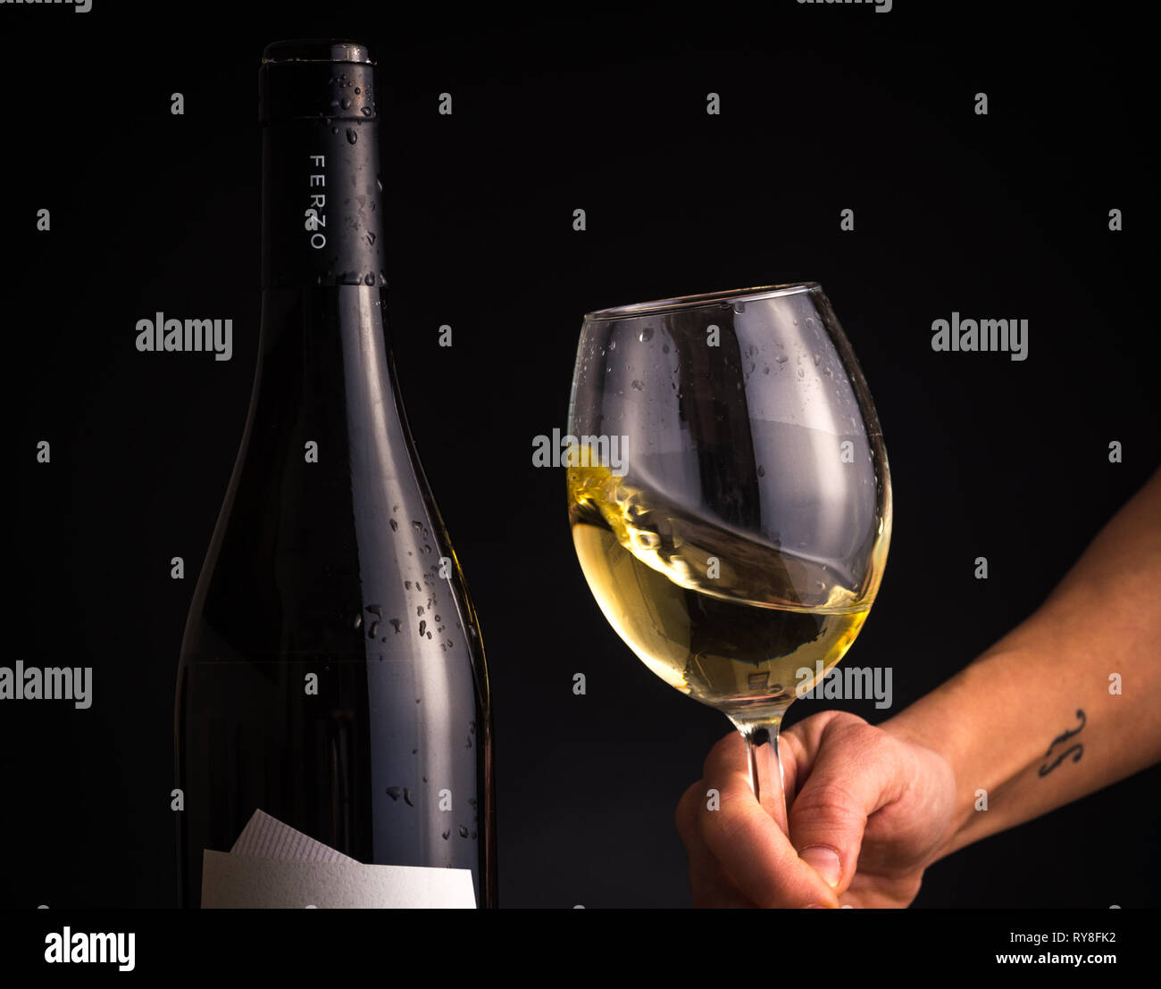 Wine glass and a bottle on dark wooden background. Stock Photo