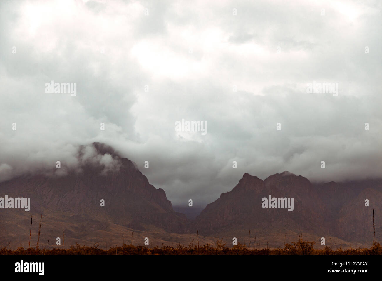 Dark and ominous clouds rolling through the widow of the Chisos Mountains in Big Bend National Park. Stock Photo