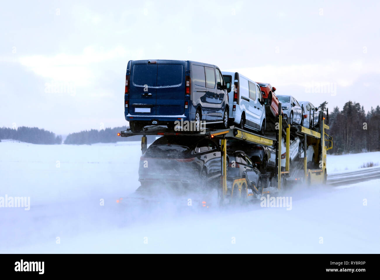 Car carrier truck transports a load of vehicles on a day of winter snowfall, rear view. Salo, Finland. January 18, 2019. Stock Photo