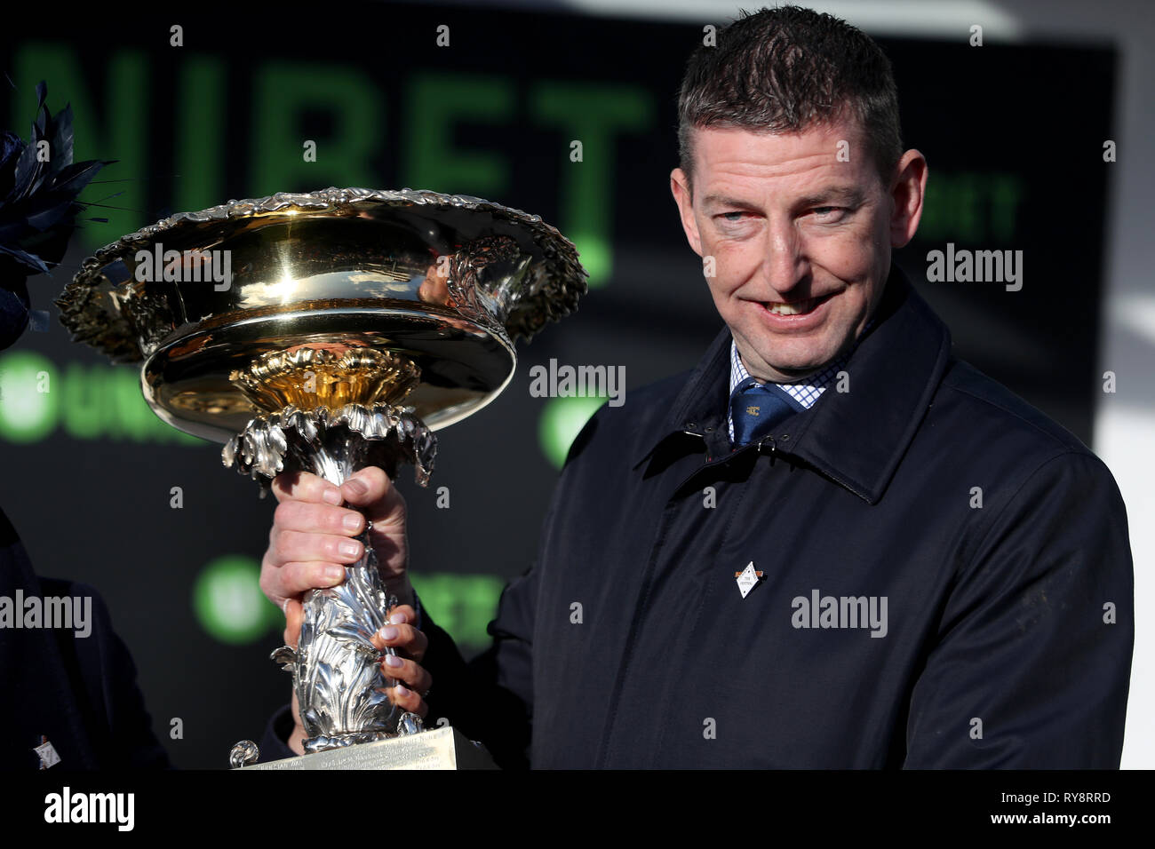 Trainer Gavin Cromwell celebrates with the Unibet Champion Hurdle Challenge Trophy after Espoir D'Allen wins during Champion Day of the 2019 Cheltenham Festival at Cheltenham Racecourse. Stock Photo