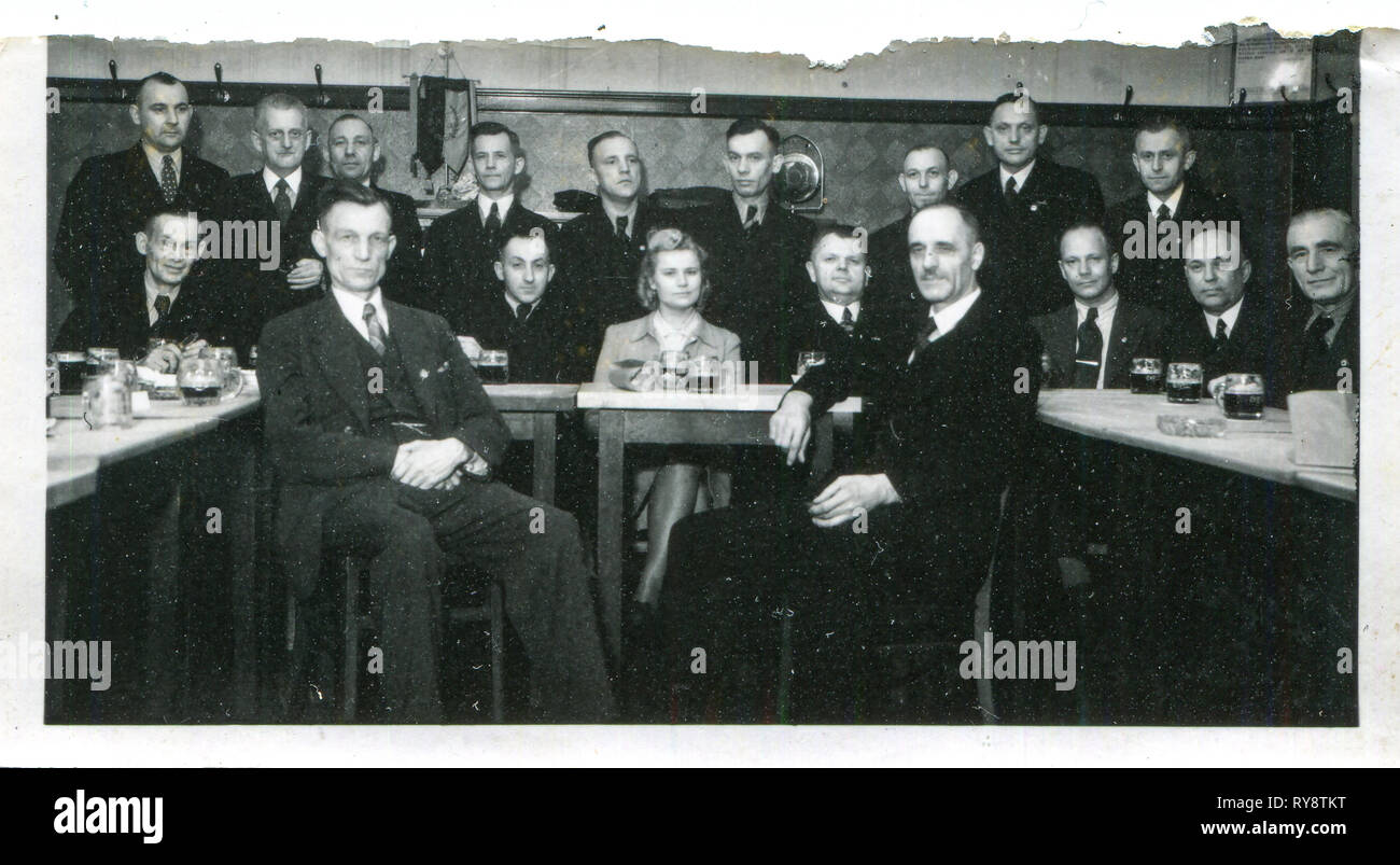 Germany. 1933s, the Third Reich, a German woman drinks beer from a bakala surrounded by 17 men. Stock Photo