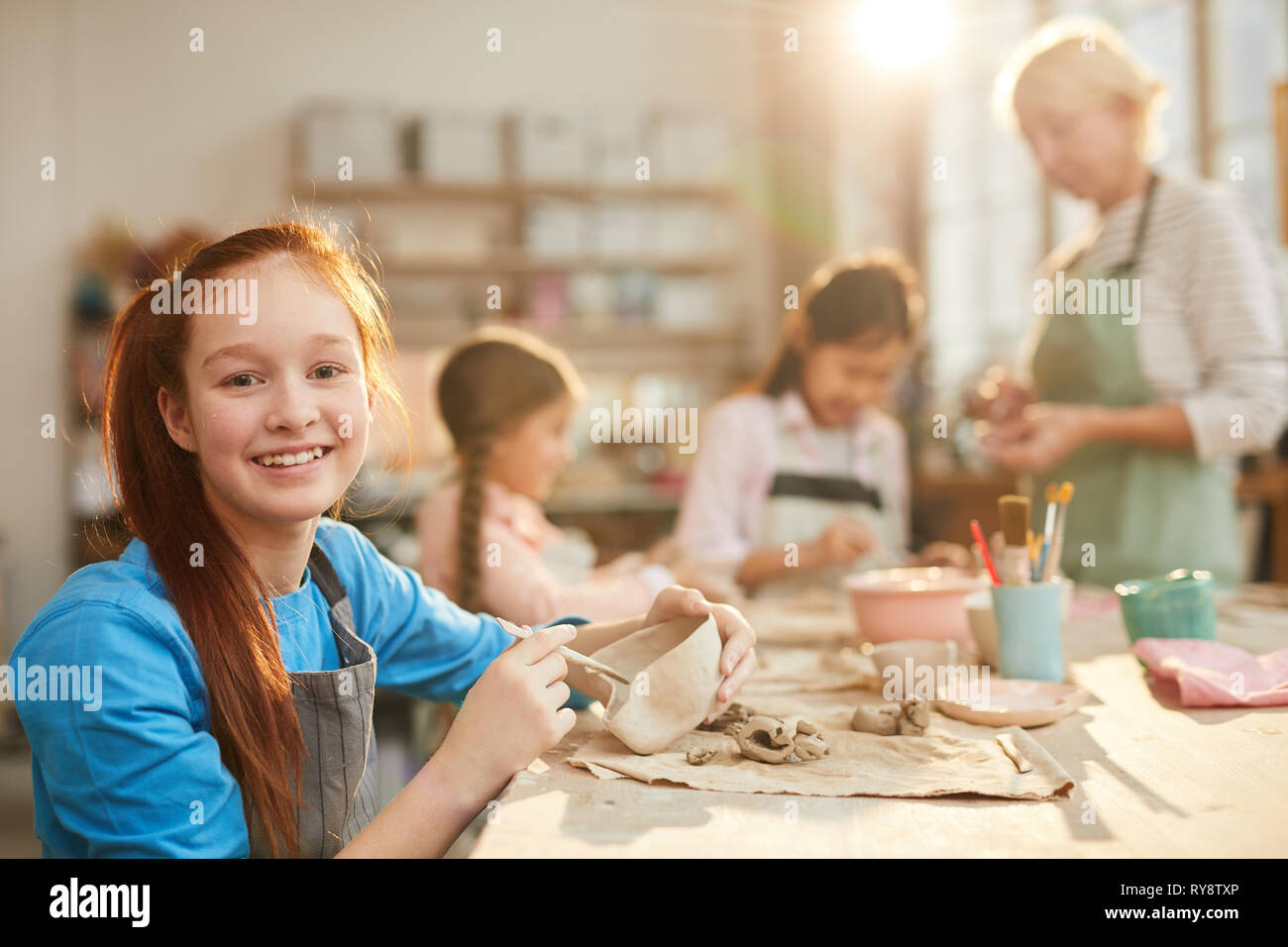 Portrait of smiling teenage girl looking at camera while enjoying ...