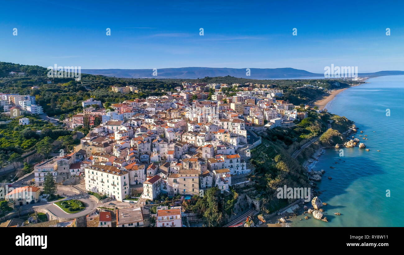 Aerial view of the white residential houses in the mountain of Rodi Italy fronting the big blue ocean on the coastal area Stock Photo