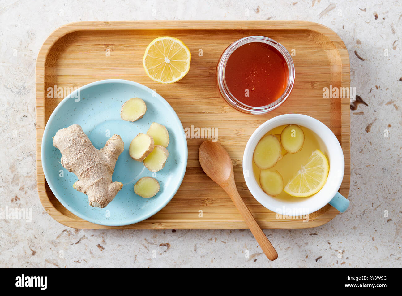 Lemon and ginger tea with honey. Wooden tray of honey lemon tea with fresh ginger root. Stock Photo