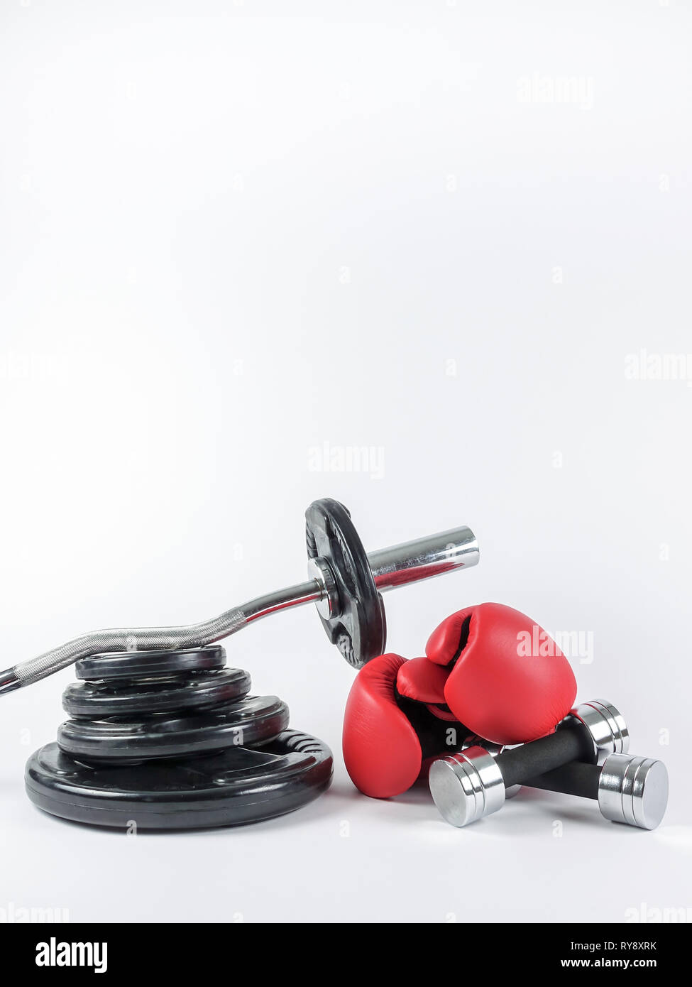 Gym gears. Weight plates, curl bar, boxing gloves and two dumbbells in a heap. Place for own text / copy space. Stock Photo