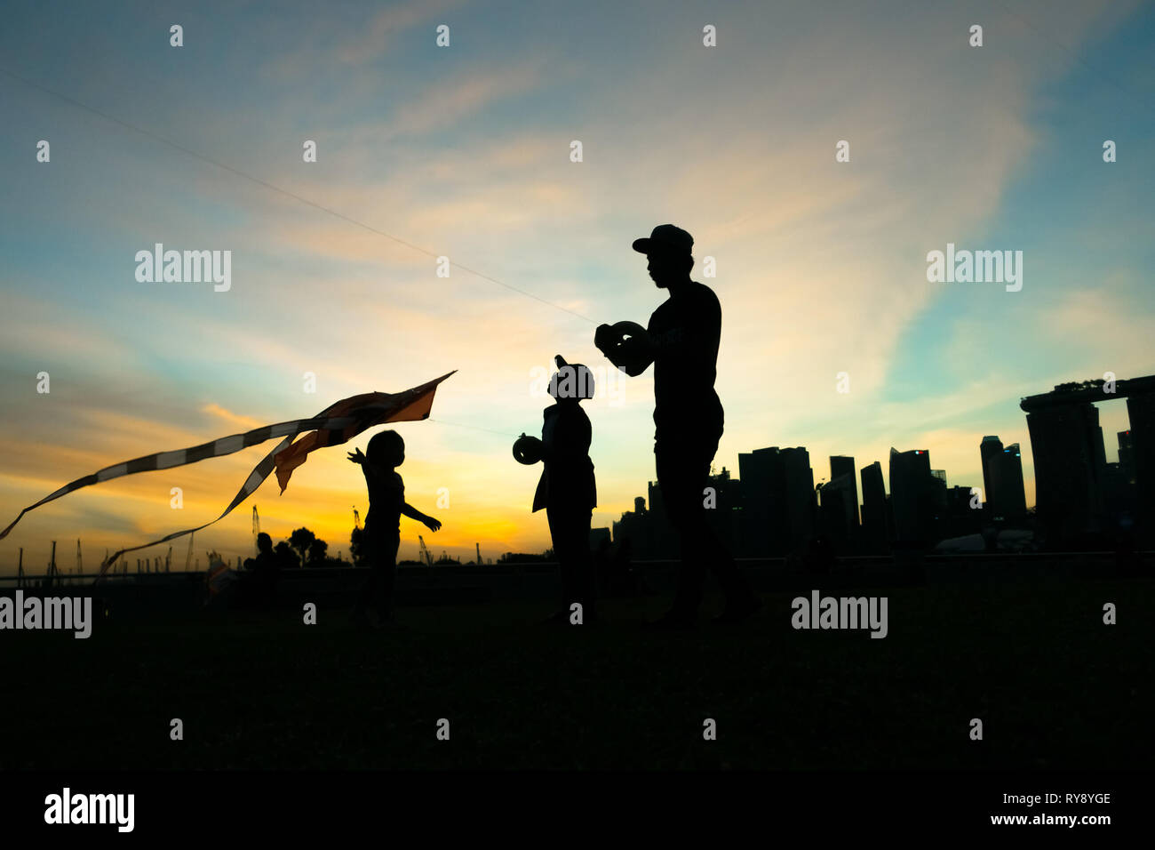 Dad flying kites with his children during sunset at Marina Barrage - Singapore Stock Photo